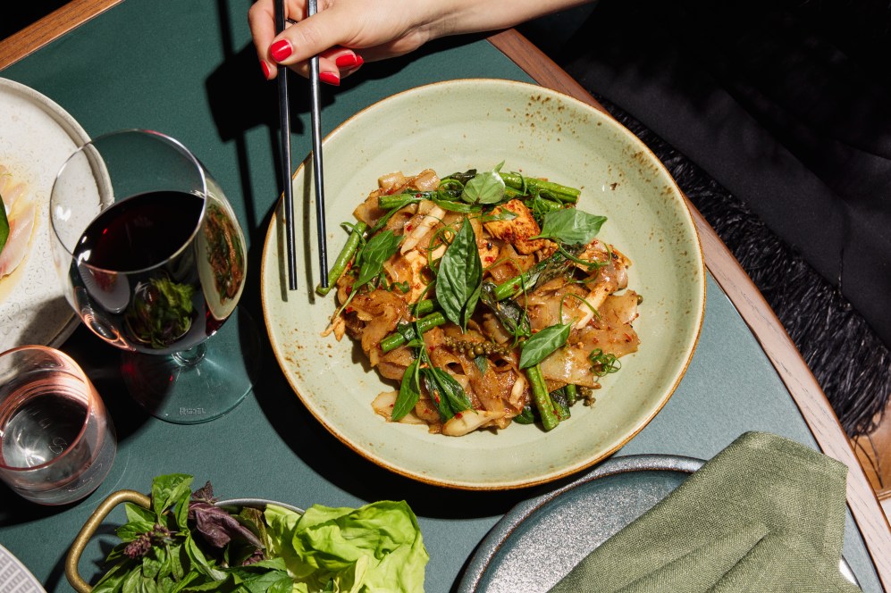 Delta Rue's Banana blossom salad in a green bowl on a dark green, timber-edged table.