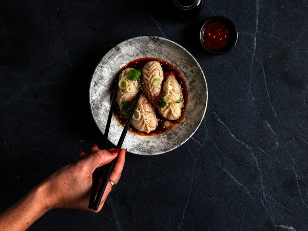 A chopstick-wielding hand picks up a MOD. Dining dumpling.