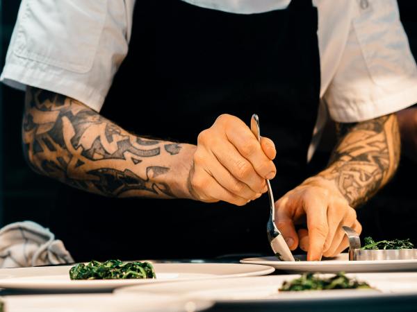 A hospitality staff member plates up dishes in the kitchen.