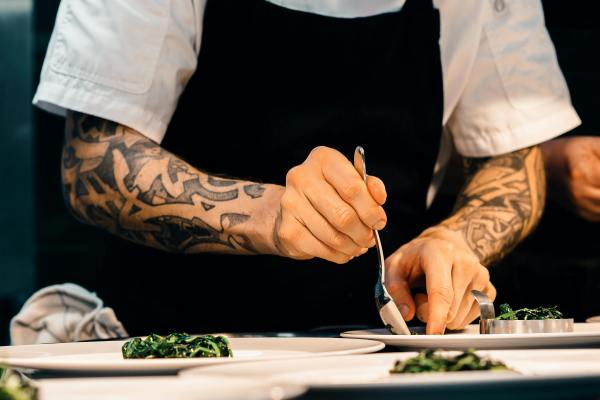 A hospitality staff member plates up dishes in the kitchen.