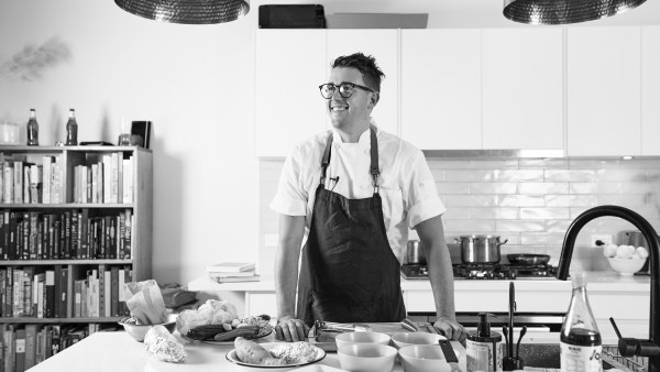 Black and white image of Chef Charlie Carrington looking away from camera and smiling in home kitchen