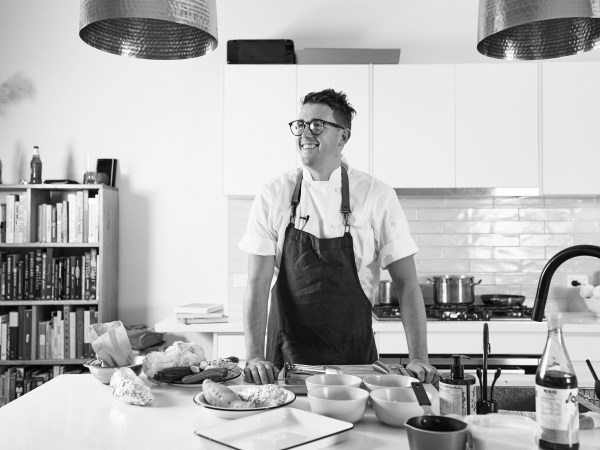 Black and white image of Chef Charlie Carrington looking away from camera and smiling in home kitchen